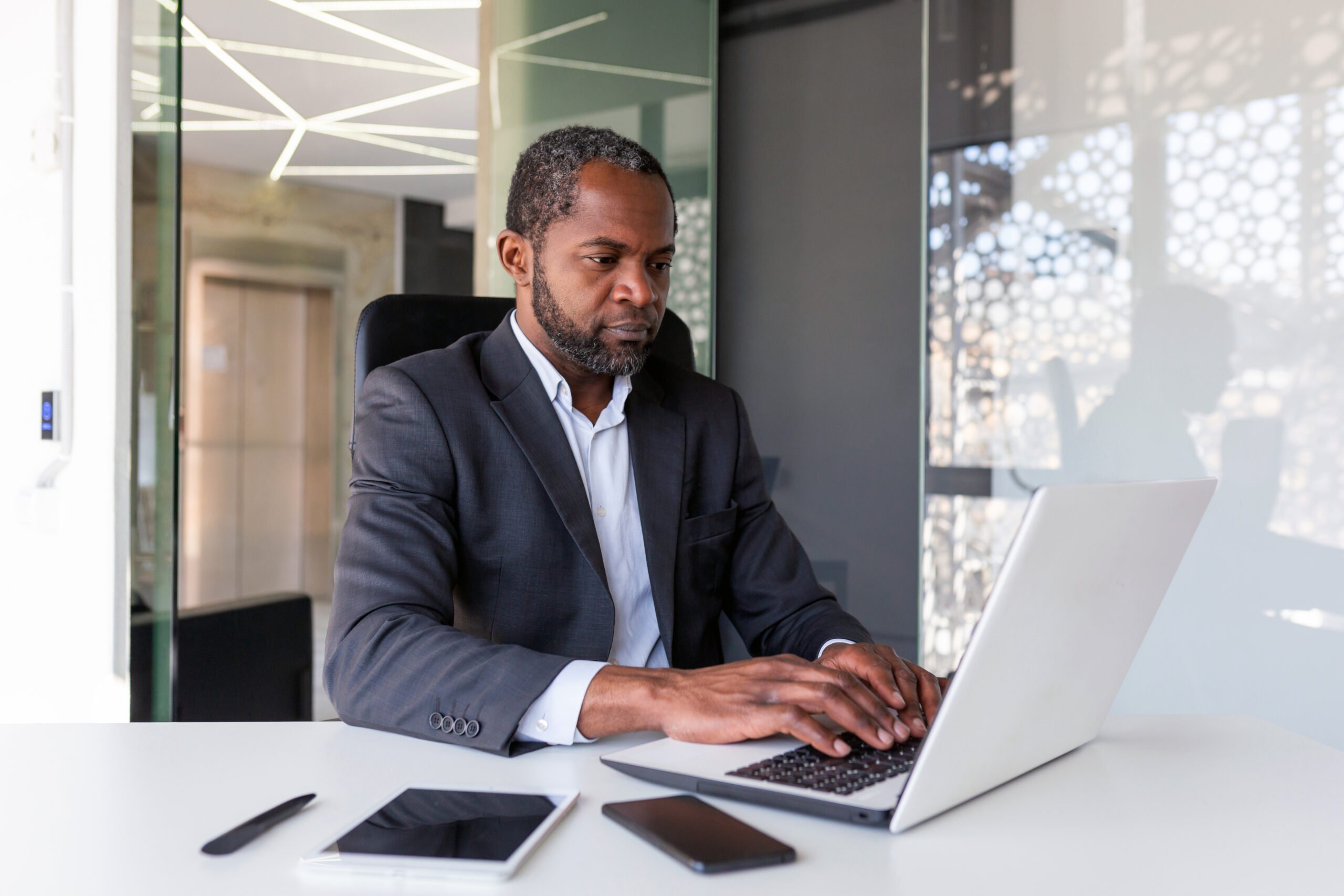 Adult Male accountancy professional working on his laptop at his desk, seated