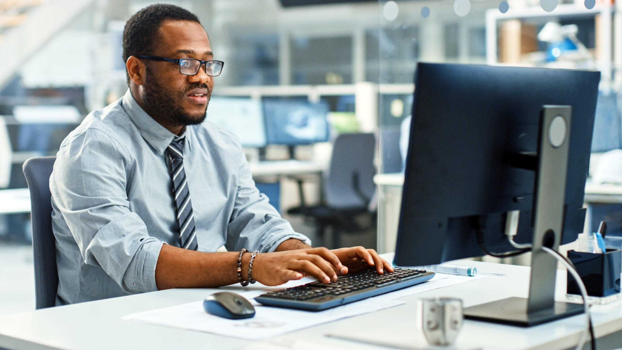 Adult male typing at his desk, Management Information Systems